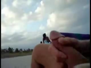 Americano turista segarsi su il spiaggia mentre donna passing da video
